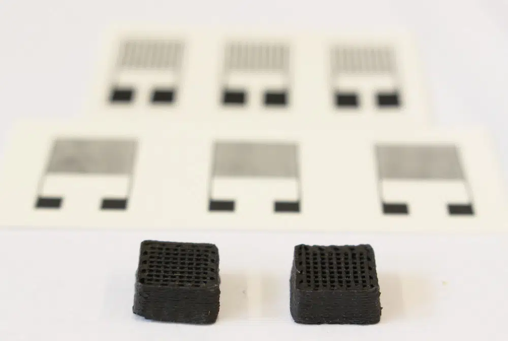 Schellack Neuartiger Werkstoff für gedruckte Schaltungen: Zwei Testquader von einem Zentimeter Breite aus dem 3D-Drucker. Im Hintergrund sieht man die gedruckten elektronischen Sensoren. | Foto: Empa